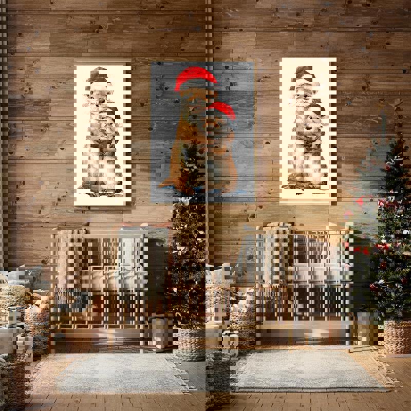 Christmas otter mother and baby canvas print in Santa hats, whimsical illustration with snowy backdrop for nursery wall decor